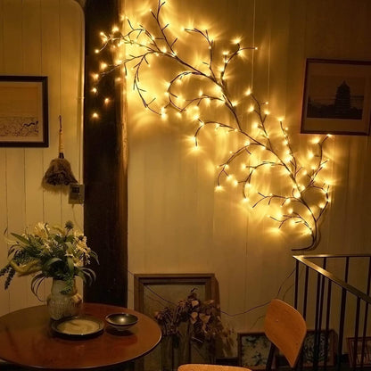 Decorative wall with illuminated branches and a small table with a vase and plate.